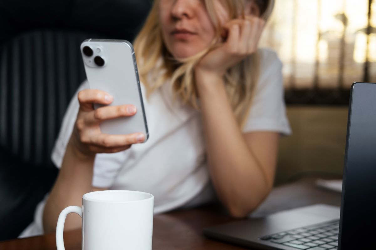 A bored young woman checks her phone.