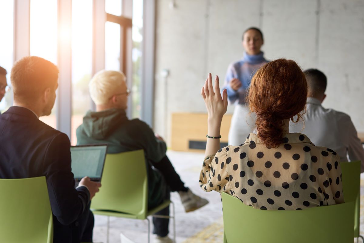 A woman raises her hand in a corporate meeting