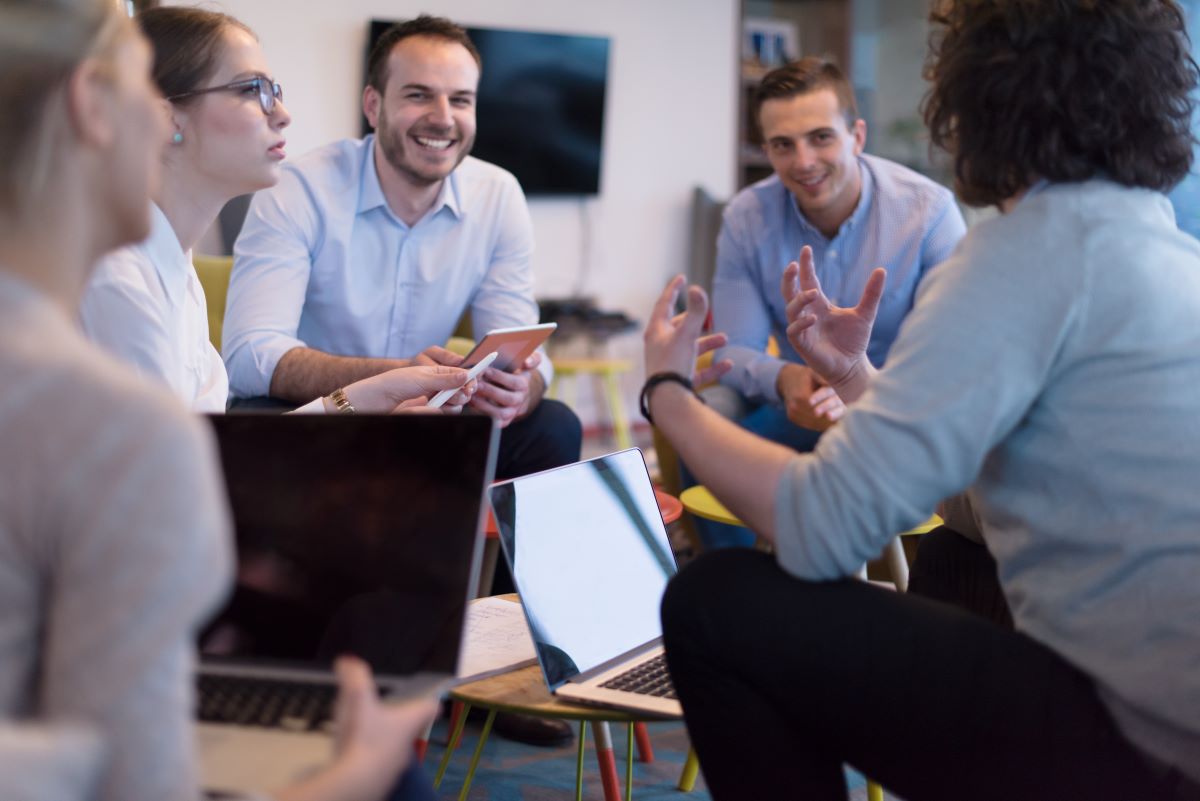 A group of employees gather around their laptops