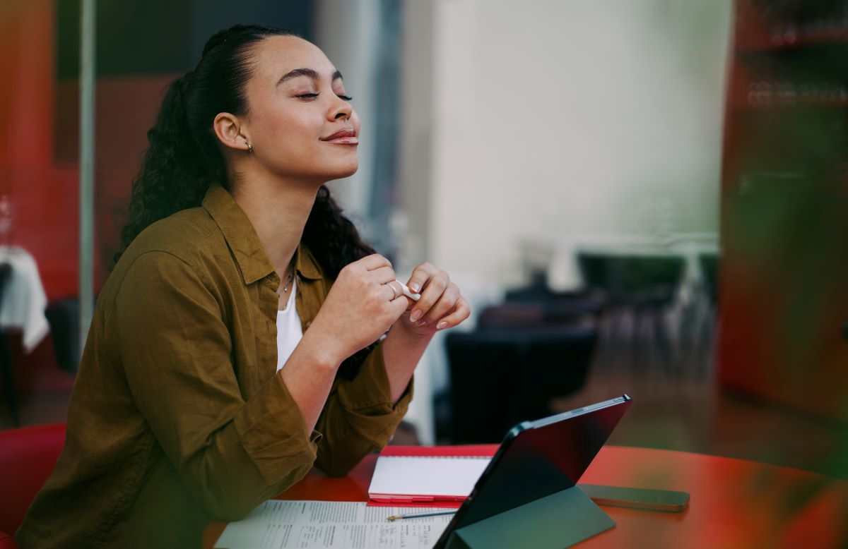 A content, smiling woman sits at her laptop.