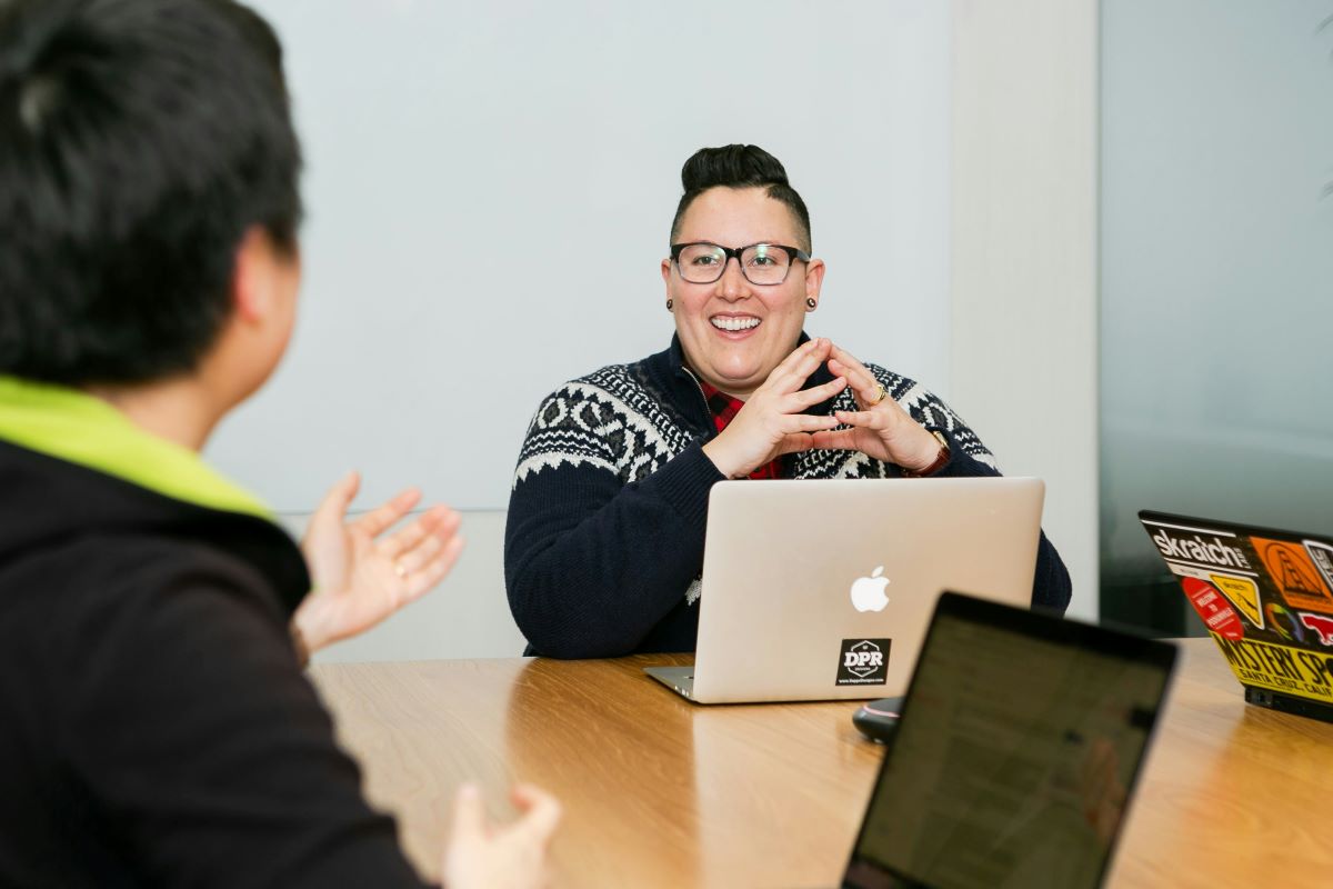 A woman sits with her laptop in a work meeting.