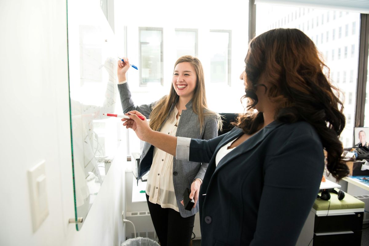 Two professionals discuss things at a whiteboard