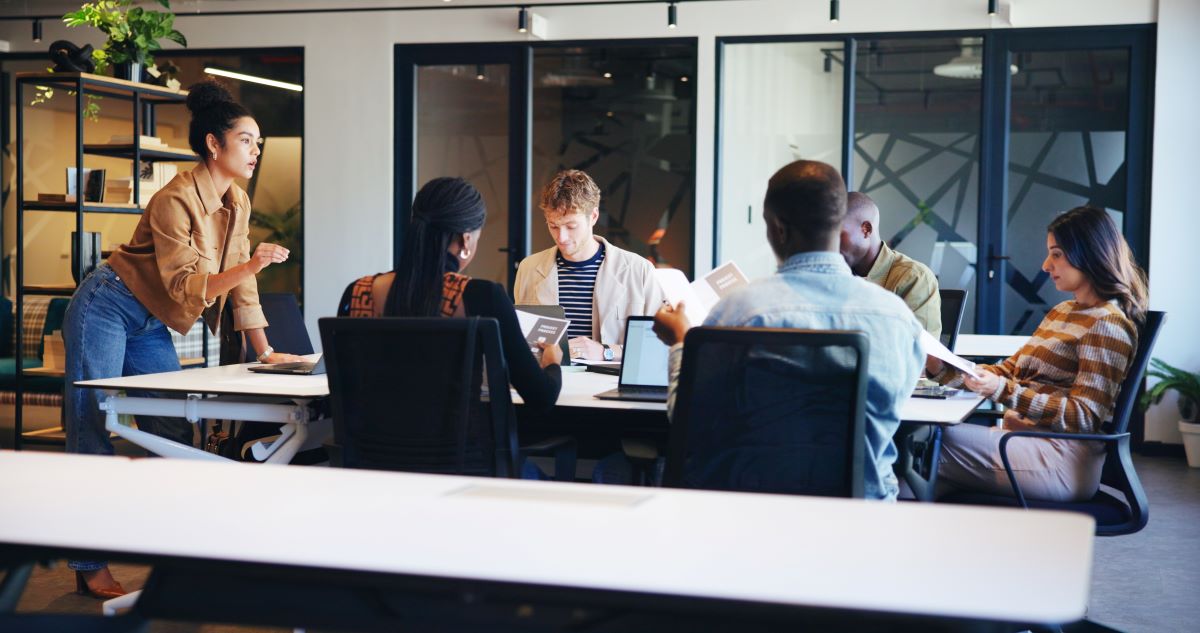 A woman presents to teammates around a board room table.