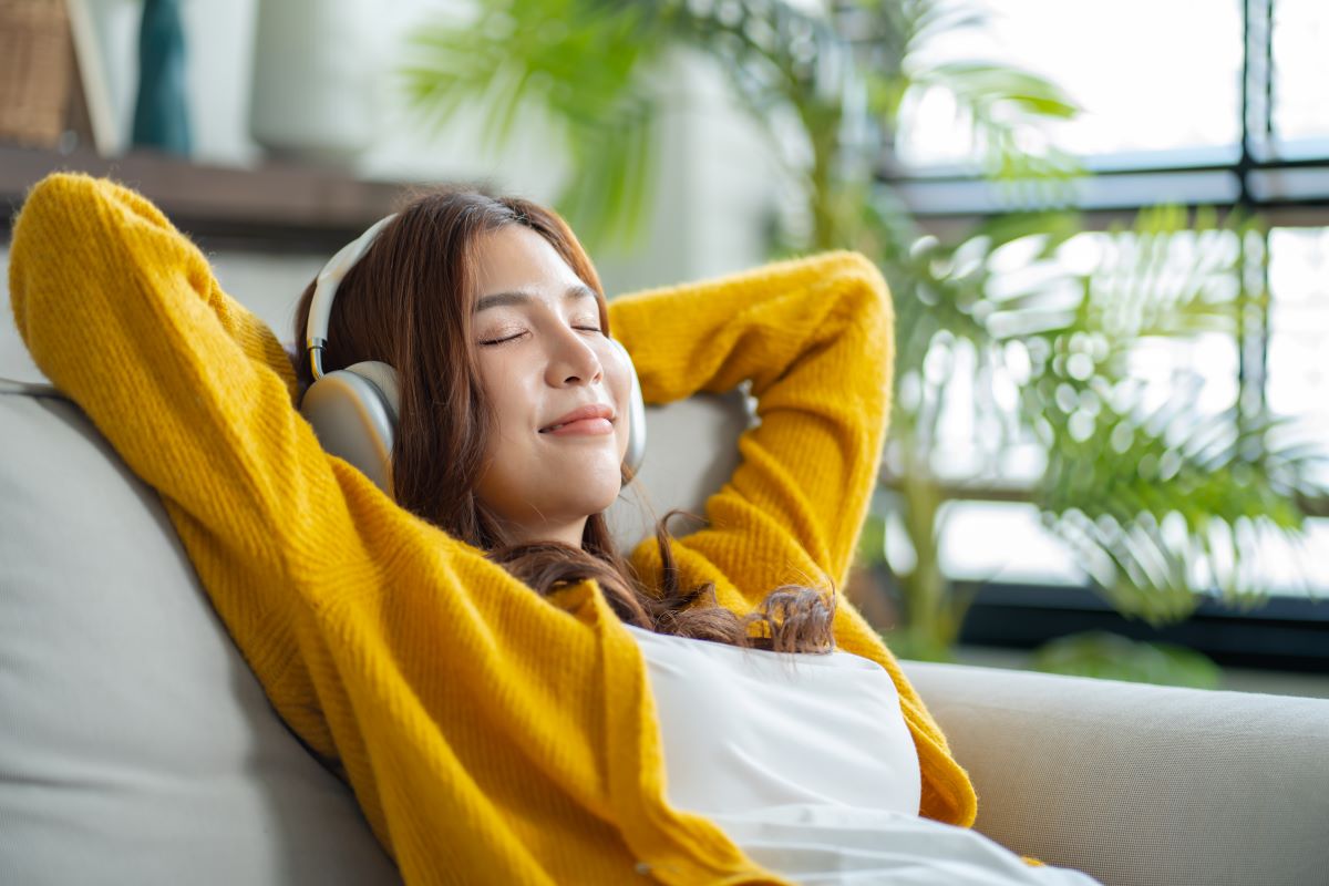 A young woman relaxes wearing headphones.