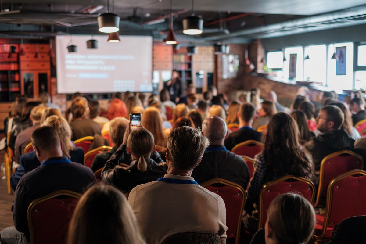 A room of work colleagues watch a presentation.