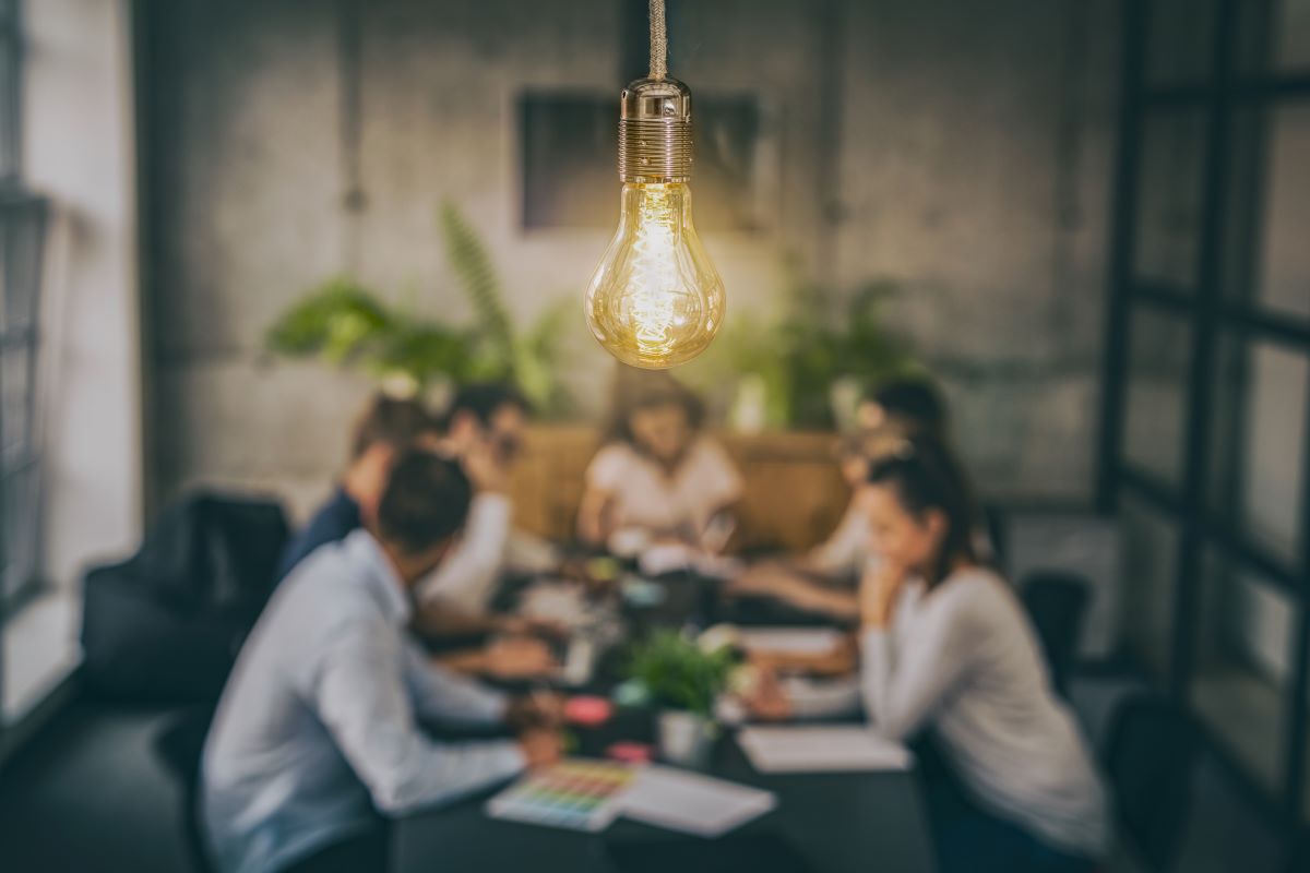 A team meeting with a lightbulb hanging prominently above.