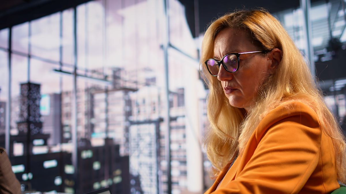 A concerned woman at work looks out of frame.